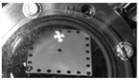 Maltese-cross shaped spot from an unfocused LaB6 cathode seen on a custom phosphor screen inside the vacuum chamber.
